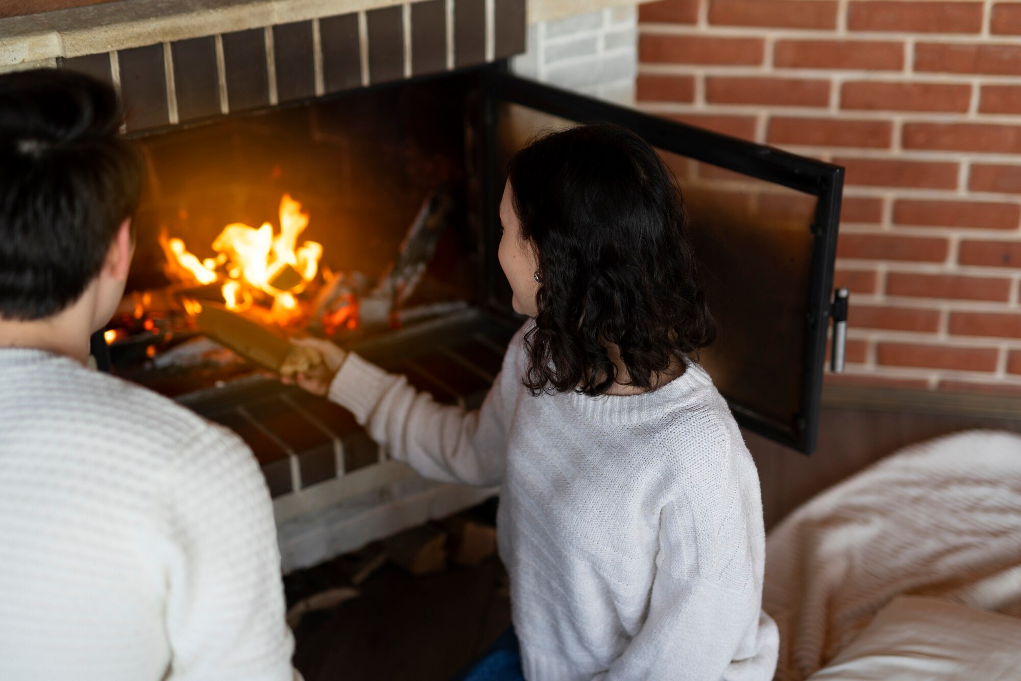 How To Sell A House With Fire Damage high angle woman putting wood in fireplace