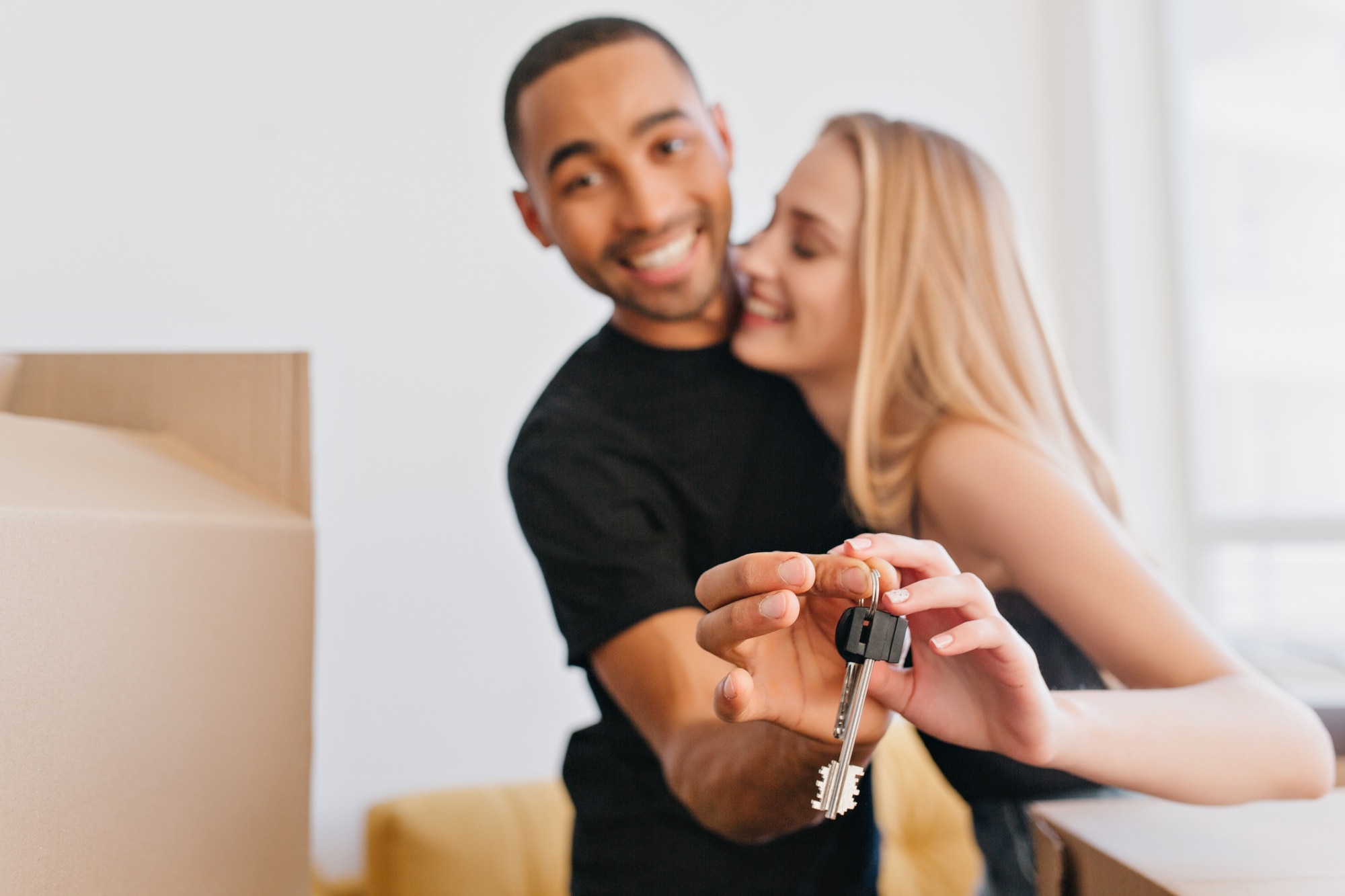 Avoid Capital Gains Tax on Inherited Property loving couple showing keys of new house going to move to new apartment bought flat packing cardboard boxes relocating