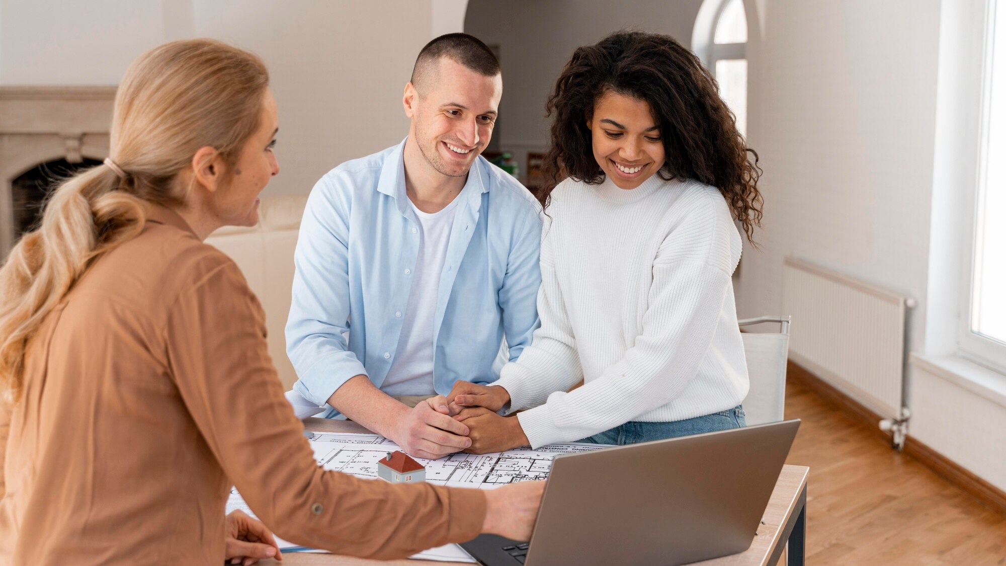 Average Real Estate Commission in California smiley realtor showing new house to couple on laptop
